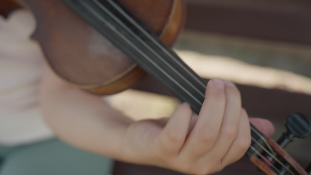Young Girl Positioning Fingers On Violin, Precise Violin Fingering Practiced In Warm Sunlight, Skilled Girl Carefully Practicing Violin Finger Placement During Sunny Daytime Session