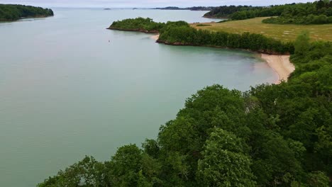 panning drone movement of arguenon tranquil coastal inlet with green forest bordering calm water and sandy beaches, saint-jacut-de-la-mer, côtes-d'armor, brittany, france.