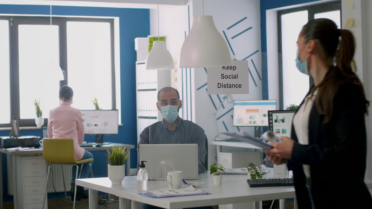 보호 얼굴 마스크를 착용 한 비즈니스 여성이 팀 온도를 확인합니다.