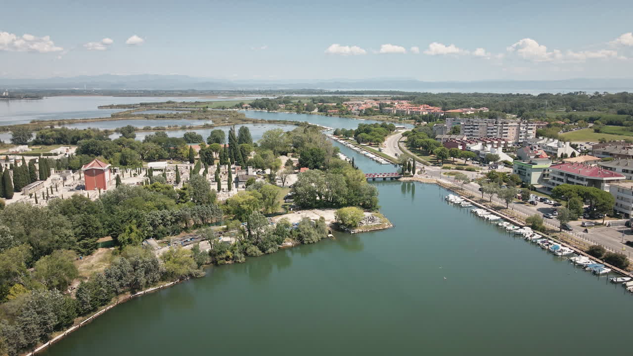 Vloeiende 4K UHD-drone vliegt vooruit over de Lagune van Grado richting de centrale grachten, jachthaven en het stadscentrum met bomen en gebouwen—ideaal voor reisfotografie, overzichtsshots