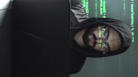 Vertical-motion-graphics-of-code-rolling-by-face-of-hacker-with-laptop