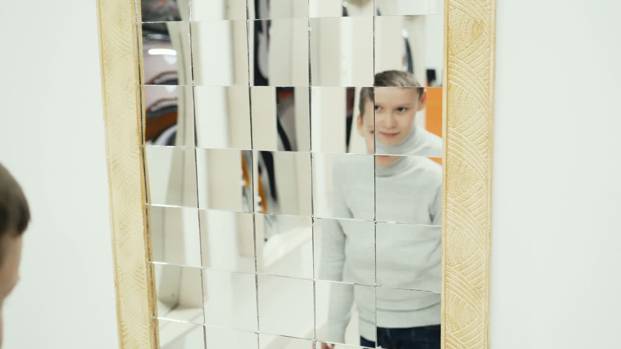 Boy playing with distorted mirror in museum of science while school excursion
