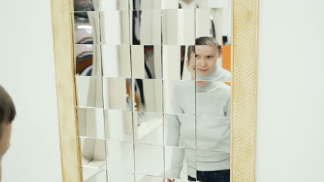 boy playing with distorted mirror in museum of science while school excursion
