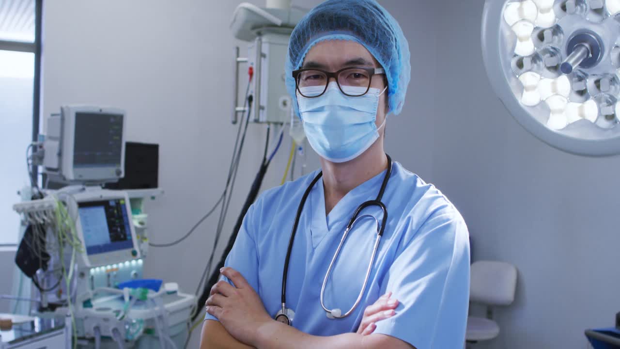 Portrait of male asian surgeon wearing face mask and scrubs in hospital