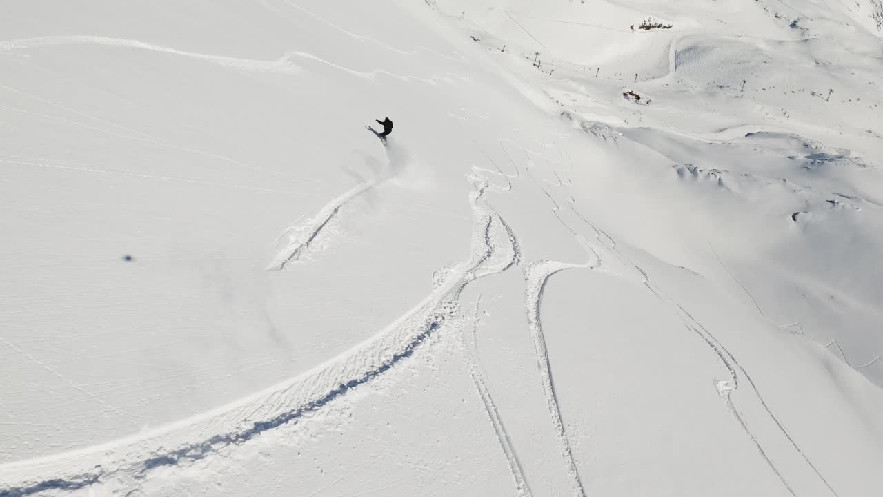 An exhilarating FPV drone shot capturing a snowboarder carving through deep powder snow on a bright winter day. The dynamic perspective highlights the snowboarder in the untouched snowy terrain