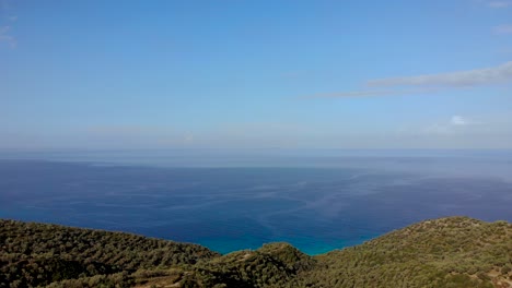 endless sea horizon with blue aquamarine water bordering green hills with olive plantations in albania