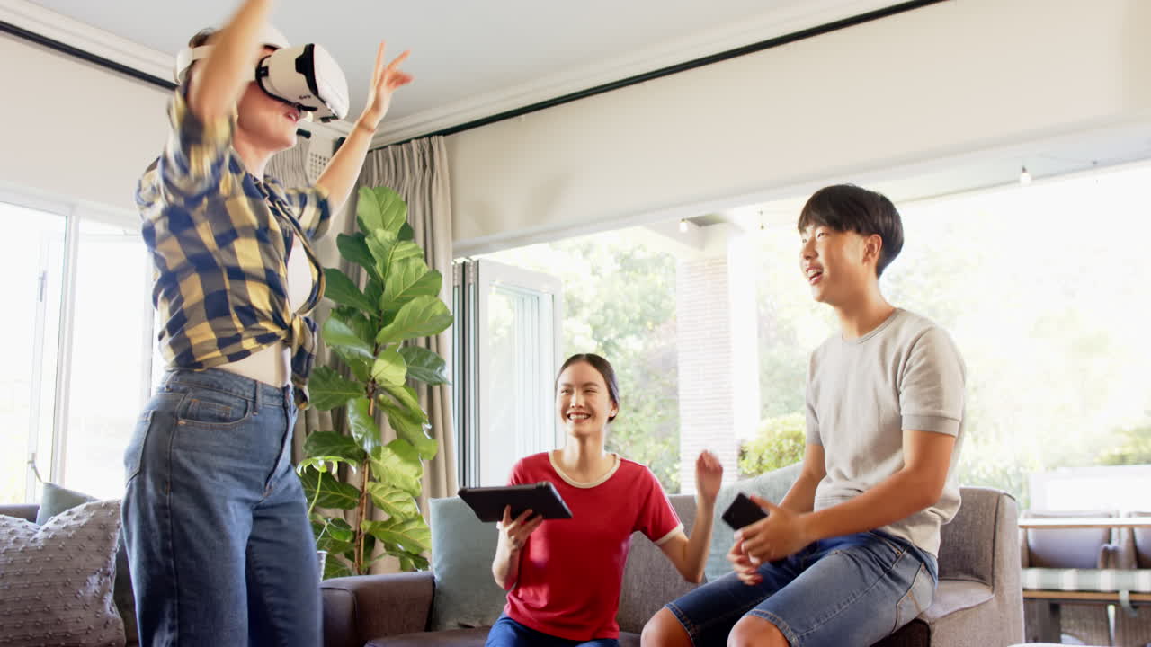 Using VR headset, woman playing virtual game while family watching and laughing