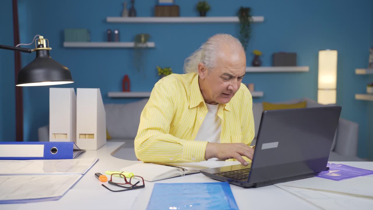 Home office worker old man working on laptop stressed.