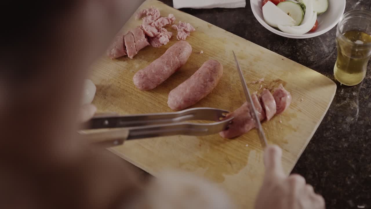 Person slicing raw sausages on a wooden cutting board