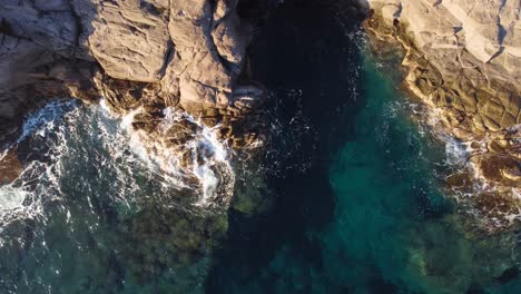 Luftaufnahme-Von-Oben-Nach-Unten-Von-Einer-Klippe,-Wunderschönem-Meer-Und-Wellen,-Die-Auf-Felsen-Krachen,-Tag