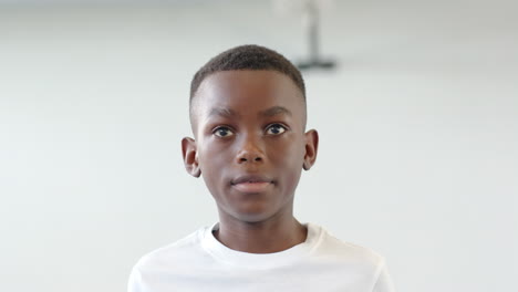 in school, young african american boy in white shirt looking thoughtful in school gym, copy space