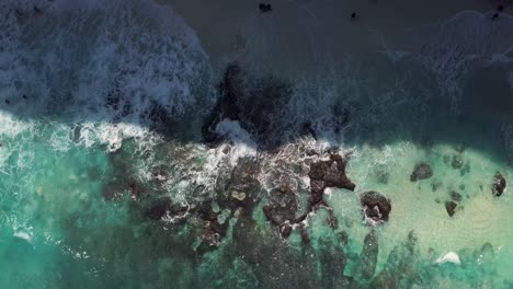 aerial view of the waves of crystal blue water hitting the shore line of diamond beach in nusa penida, indonesia