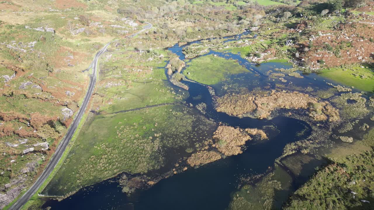 Wide revealing drone shot of Gap of Dunloe, Bearna an Choim&iacute;n, narrow mountain pass in County Kerry, Ireland, that separates the MacGillycuddy's Reeks mountain range and the Purple Mountain Group