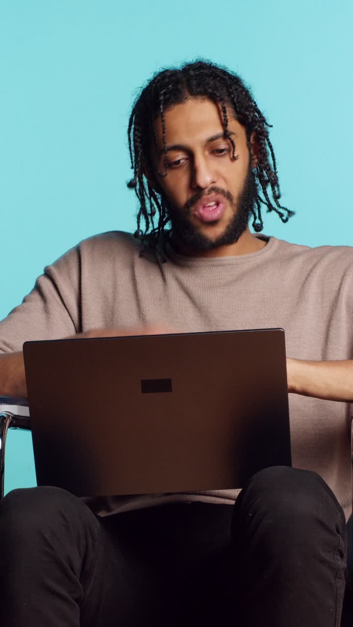Vertical video Man composing email, typing on laptop keyboard, studio ...