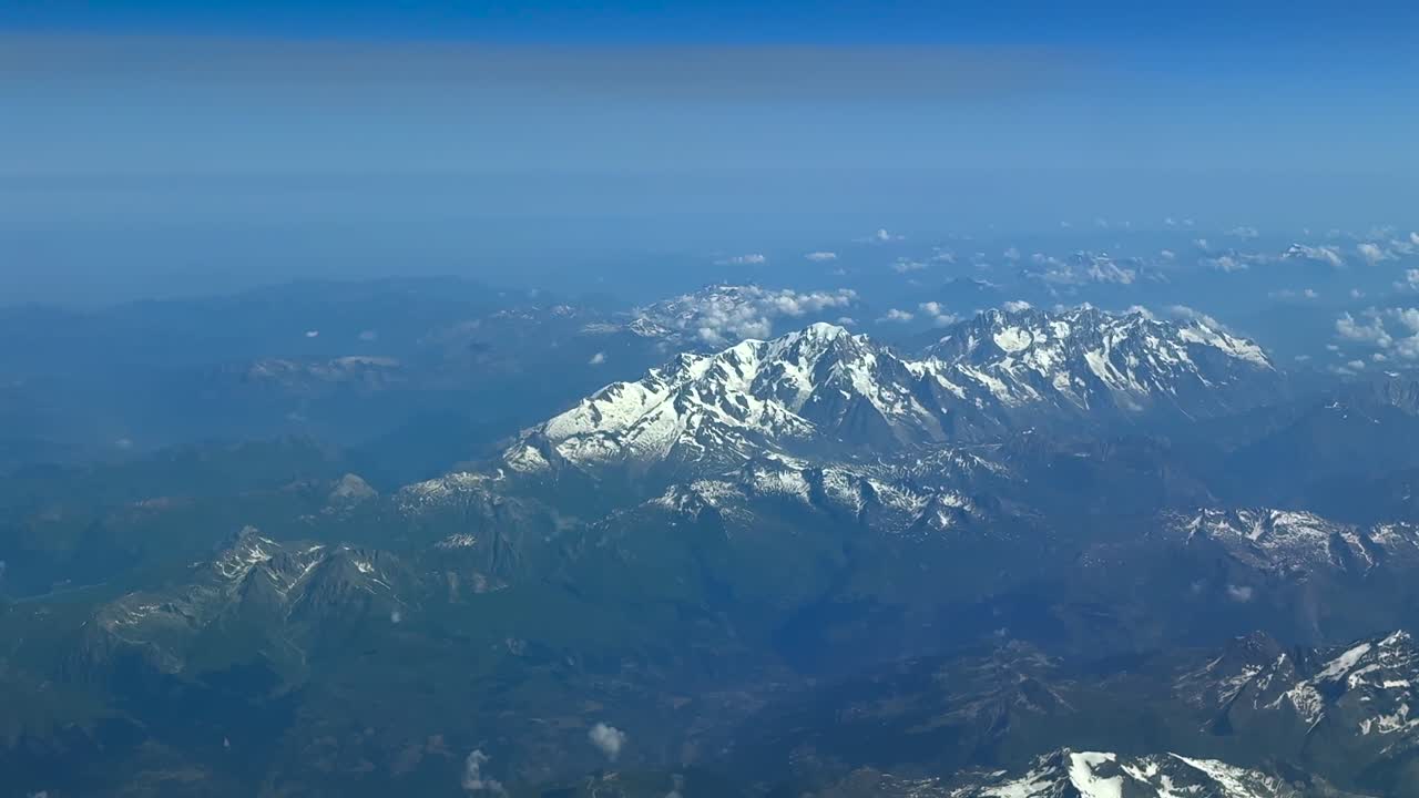 Vue aérienne plongeante des Alpes suisses prise depuis le cockpit d’un jet volant au coucher du soleil par une journée d’été brumeuse
