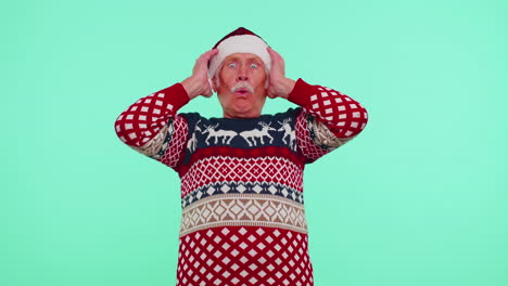grandfather in new year deer sweater raising hands in surprise shocked by sudden victory wow emotion