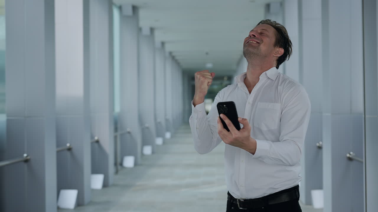 Successful Businessman Celebrating Good News on Smartphone