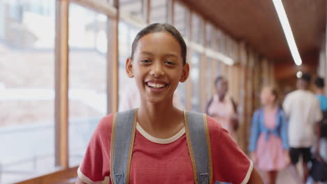 smiling student with backpack in school hallway, enjoying break time