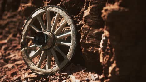 old wooden cart wheel on stone rocks