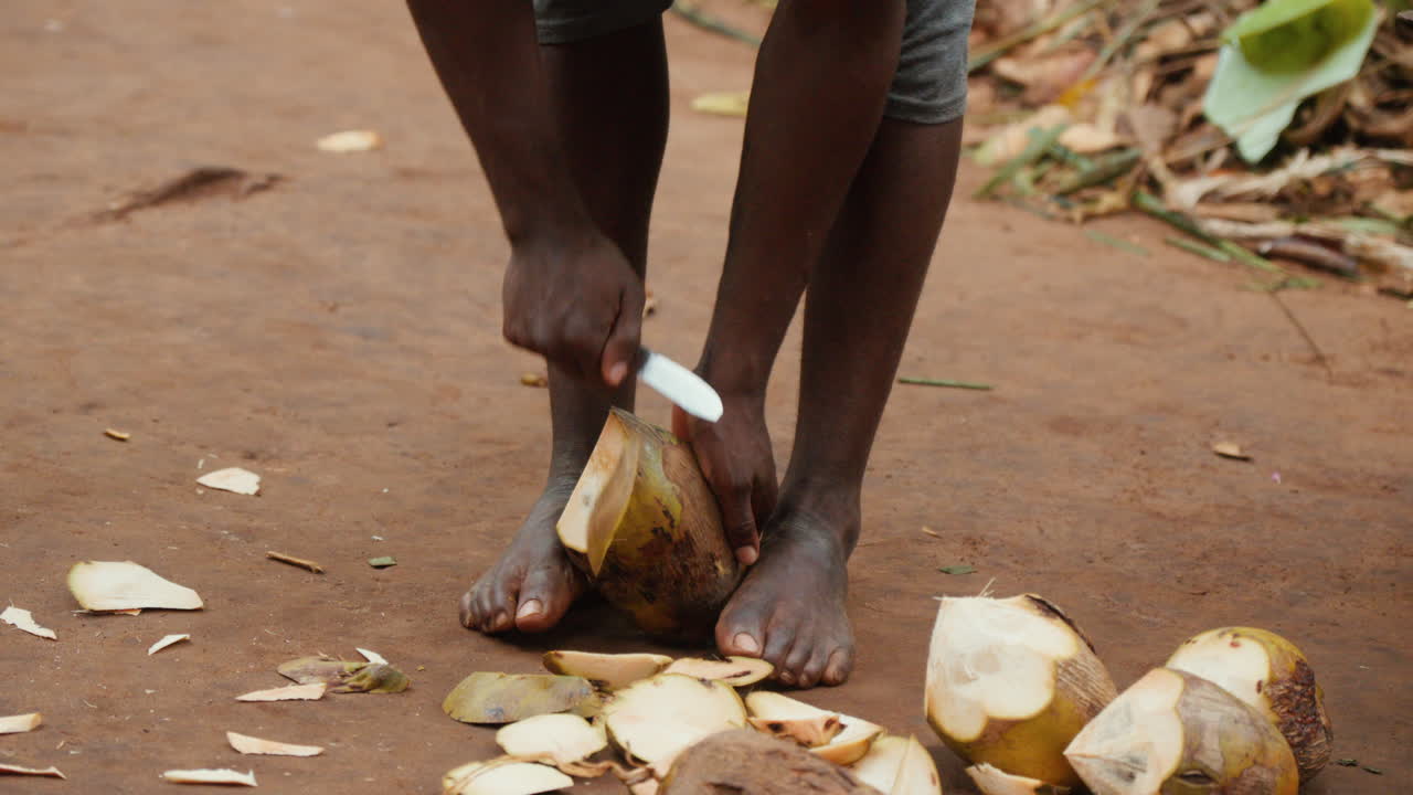 African man cutting a coconut with a knife