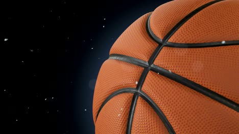 hermosa pelota de baloncesto girando de cerca en cámara lenta en negro con partículas de polvo volando. animado en bucle baloncesto 3d de la pelota girando. 4k uhd 3840x2160.