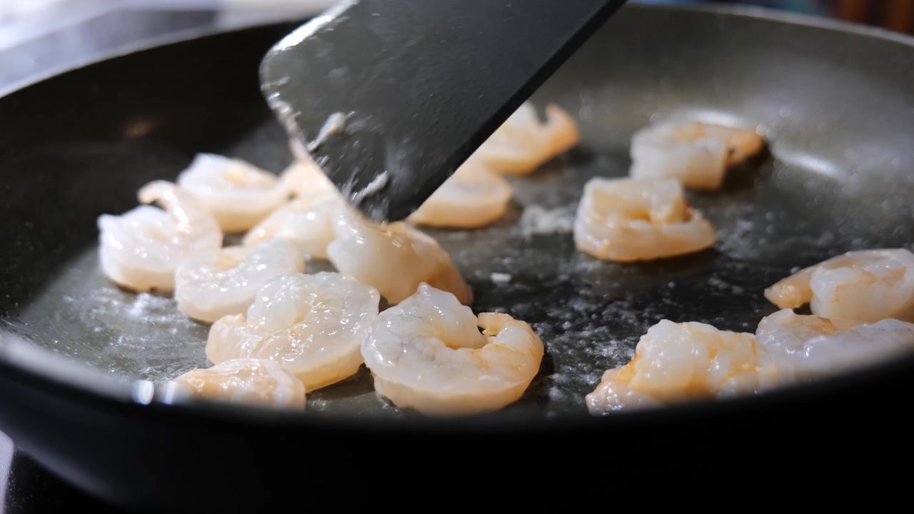 Primo piano di gamberi che friggono in padella con olio. Concetto di cucina