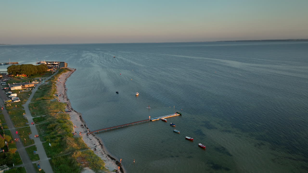 vista aérea de una zona costera con una playa, barcos y un muelle que se extiende en el agua durante la puesta de sol - kuźnica