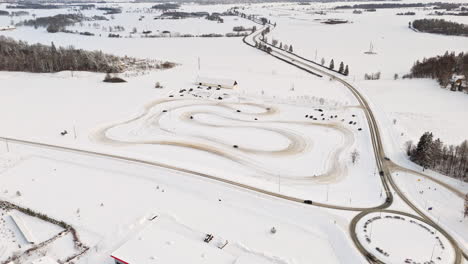 panoramic drone shot of cars driving on a ice track on the snowy countryside