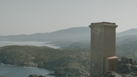 panoramic view of a tower near cap de creus where a lot of seaguls are circling around and people walking by