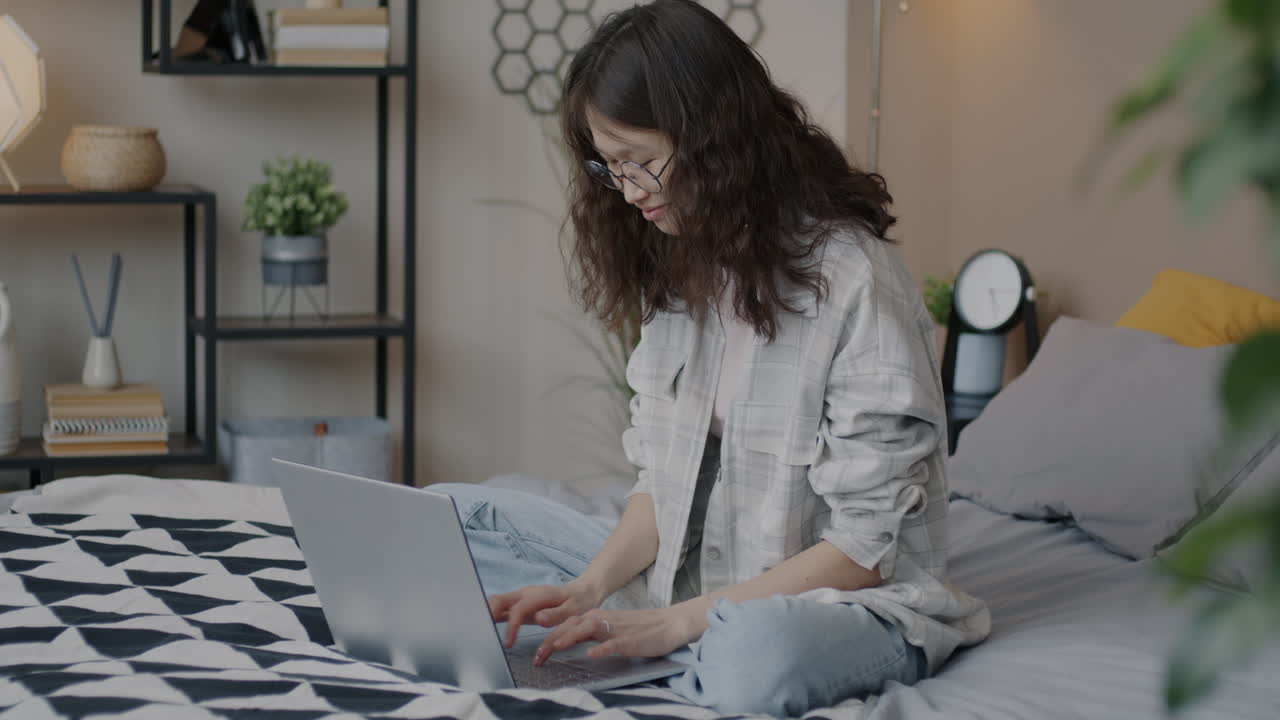 mujer joven trabajando en una computadora portátil en el dormitorio