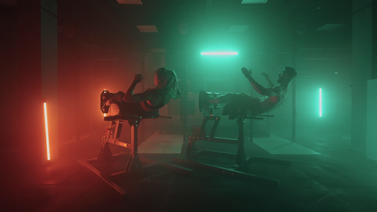 남자와 여자가 체육관에서 함께 몸을 들어 올리는 복부 운동을 합니다. 두 사람이 함께 복부 운동를 합니다.