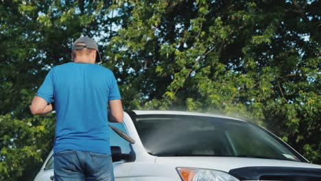 Un-Hombre-Lava-Su-Auto-En-La-Vista-Trasera-Del-Patio-Trasero