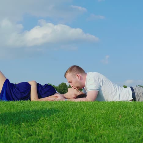 el joven esposo con su esposa embarazada se relaja en el parque juntos yace sobre la hierba verde 1