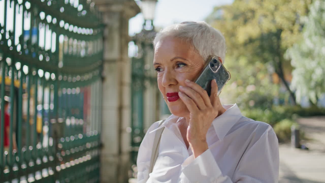 Senior businesswoman speaking cell in park closeup. Beautiful short hair lady