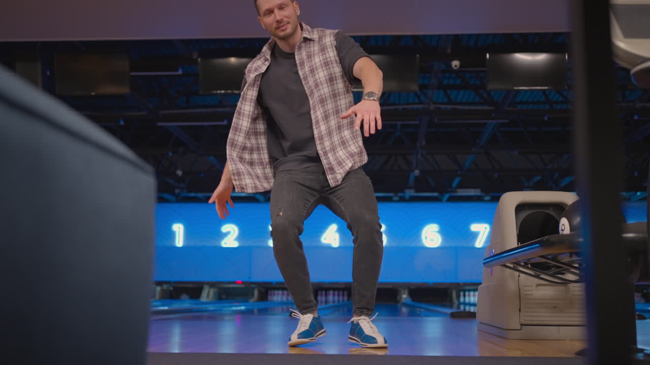 A man dances a victory dance in a bowling club. Celebrating by doing a somersault. Knocked out strike in bowling