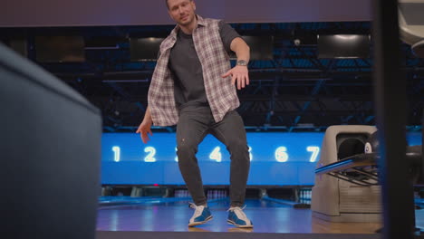 a man dances a victory dance in a bowling club. celebrating by doing a somersault. knocked out strike in bowling