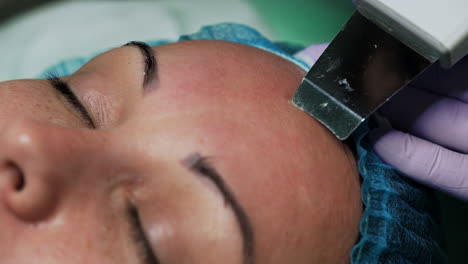 beautician performs ultrasonic face skin cleansing using special device. skincare concept. extreme close up.