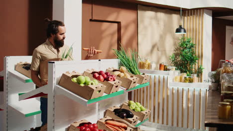 el hombre inspecciona y huele las verduras de la tienda biológica.