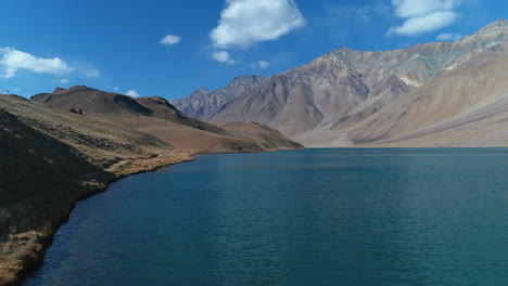 drone flying close to a mountain lake on a bright, sunny autumn morning