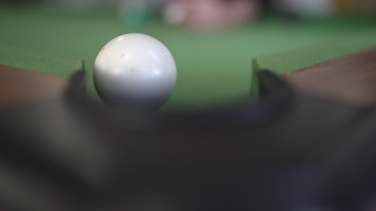Una imagen de primer plano captura el detalle de una mesa de billar con una bola blanca golpeando y desplazando otra bola.