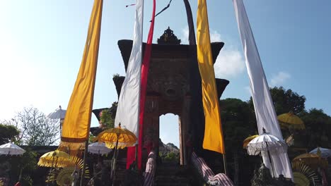 entrance to samuan tiga temple in bali indonesia, ancient architecture with colorful religious flags, clear skyline
