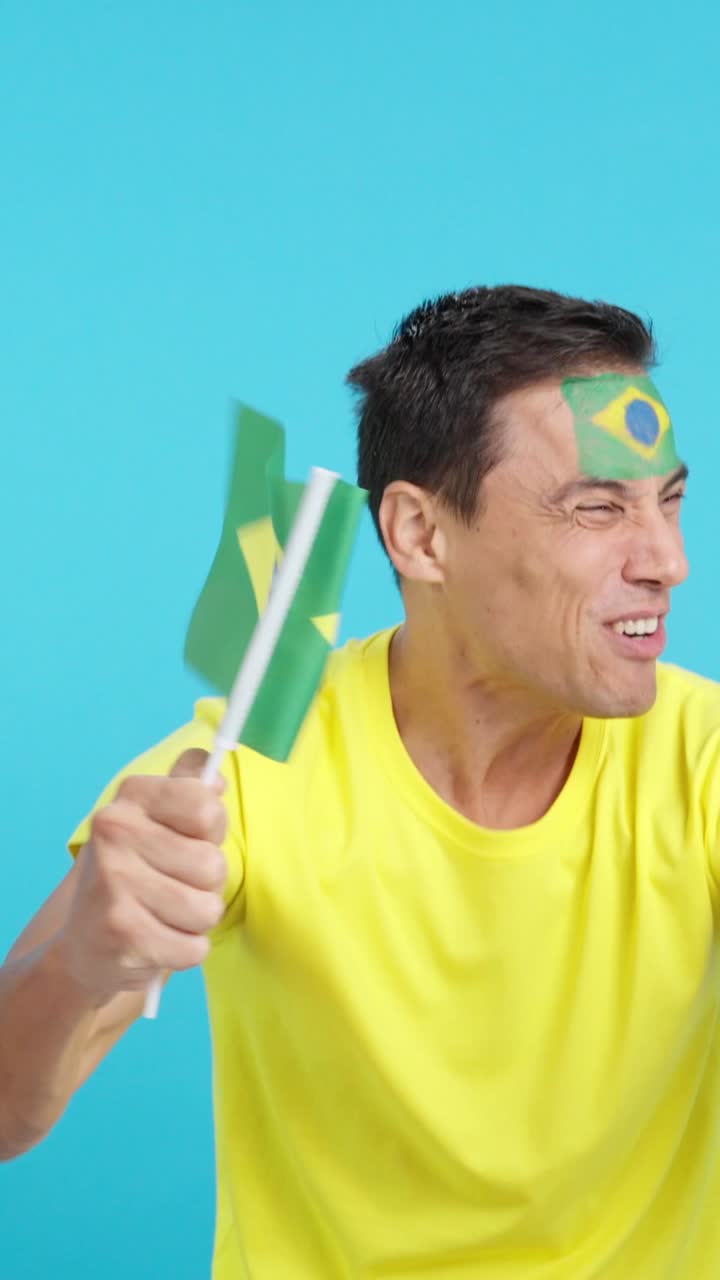 Passionate brazilian supporter screaming and waving a national flag