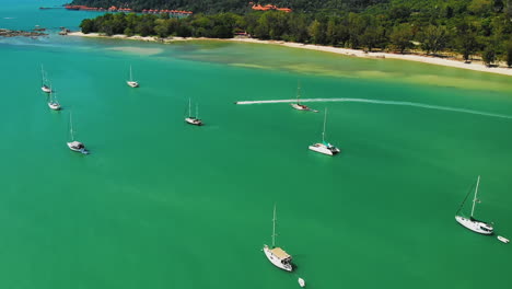 Zwei-Schnelle-Jetskis-Fahren-Auf-Klarem,-Türkisfarbenem-Wasser-In-Der-Nähe-Eines-Tropischen-Strandes-Vorbei