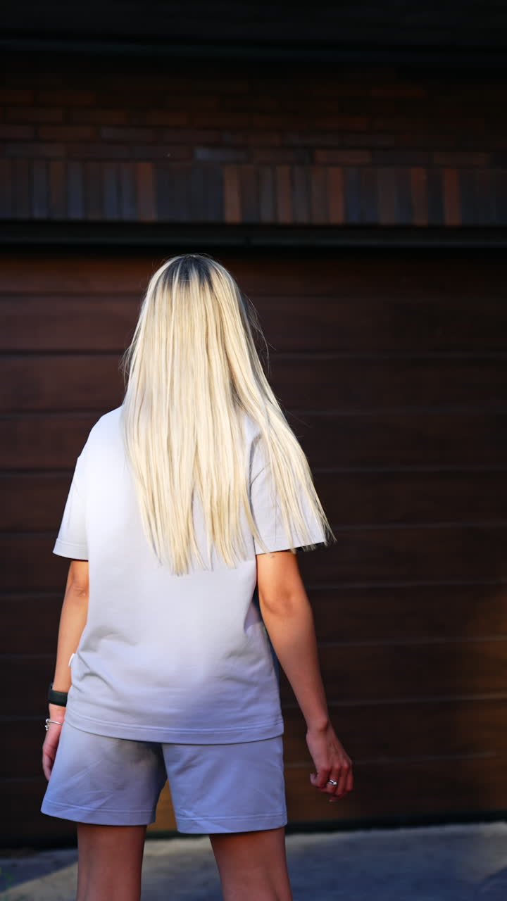 Caucasian female model turns around in front of camera. Blonde woman demonstrate summer sports wear. Vertical video