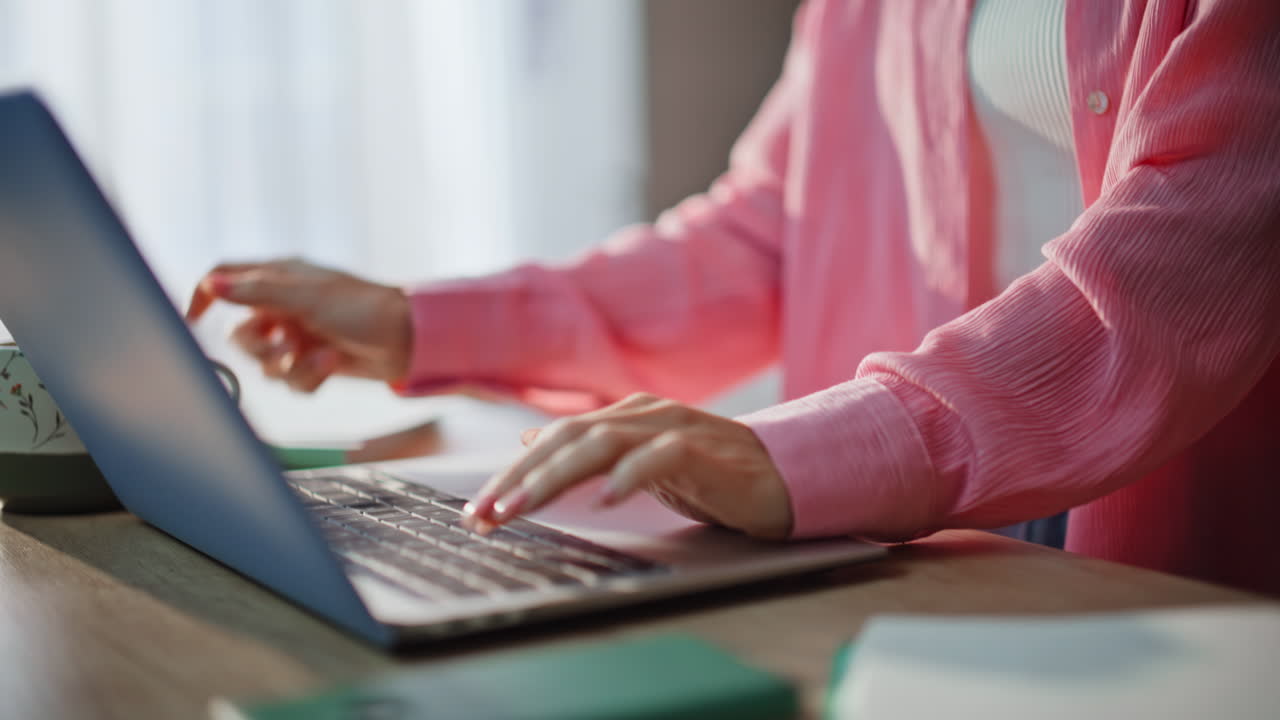 Closeup hand making notes in copybook texting computer online. Lady drinking tea