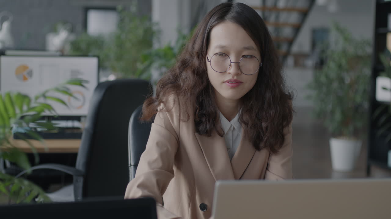 mujer joven trabajando en una computadora portátil en una oficina moderna