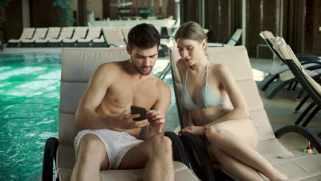 Closeup-couple-lying-on-loungers-with-phones.-Family-watching-photo-together
