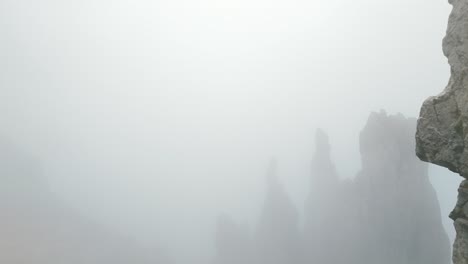 lombardía, italia - una escena hipnotizante de las escarpadas y escarpadas cimas de grignetta cubiertas de niebla - toma aérea de retroceso