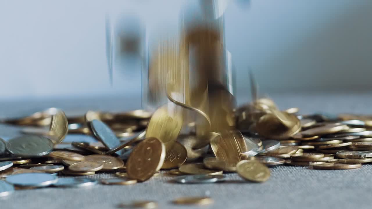 large number of coins dropping on to a table and filling the surface. Close Up
