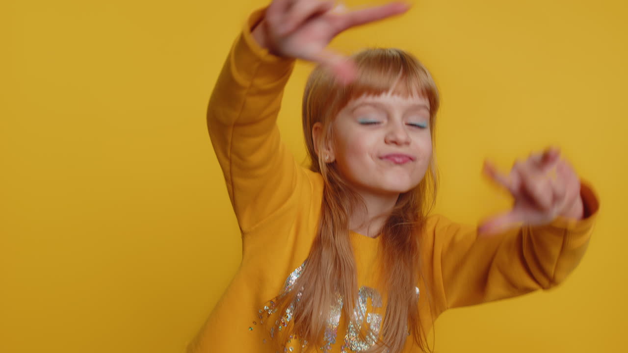 Happy child girl kid showing rock n roll gesture by hands, dancing, rejoicing in success, cool sign